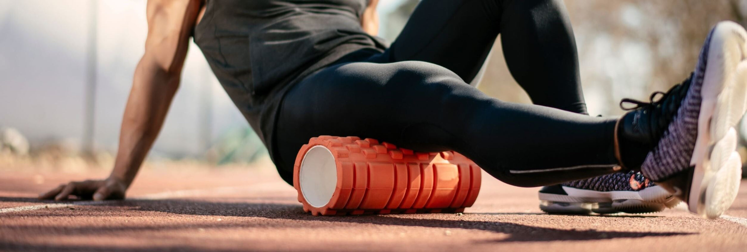 Young man doing an exercise with foam roller on her right leg