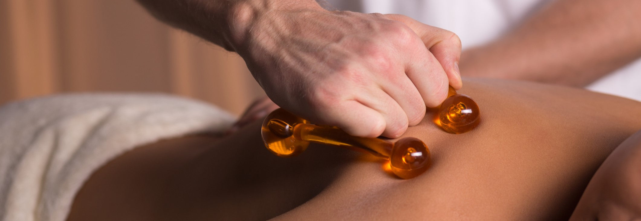 A woman receiving soft tissue treatment on her back using a back massager
