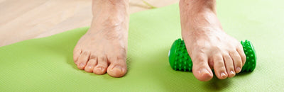 Man doing flatfoot correction exercise using a foot massager
