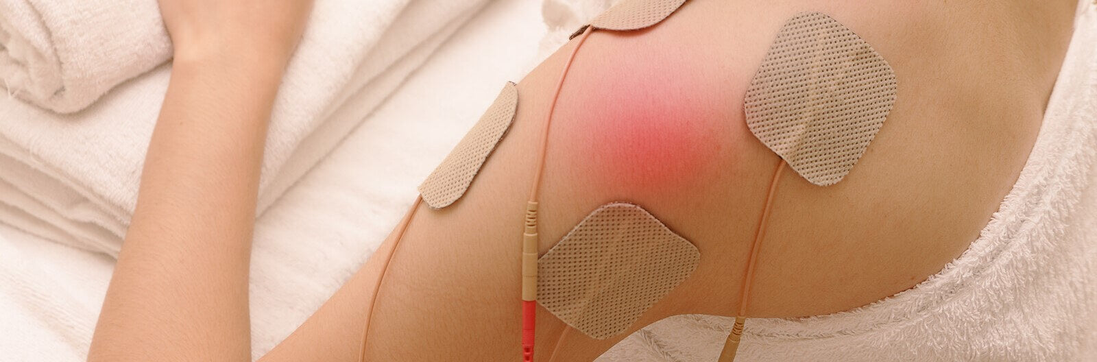 Woman using EMS machine on her shoulder