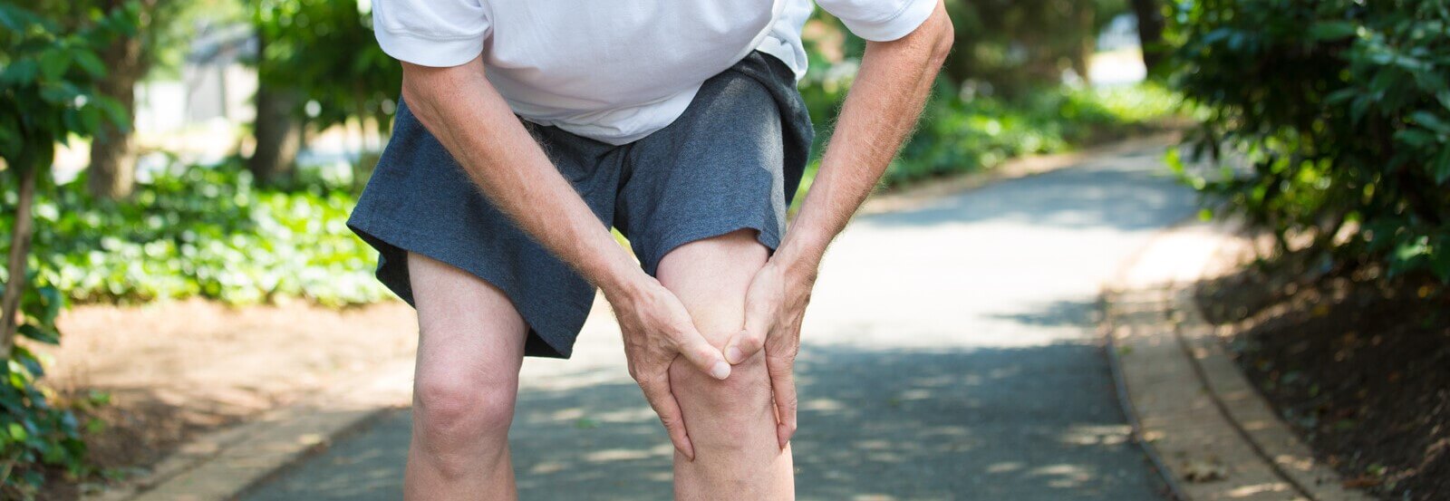 A man with MCL and LCL knee pain holding his knee