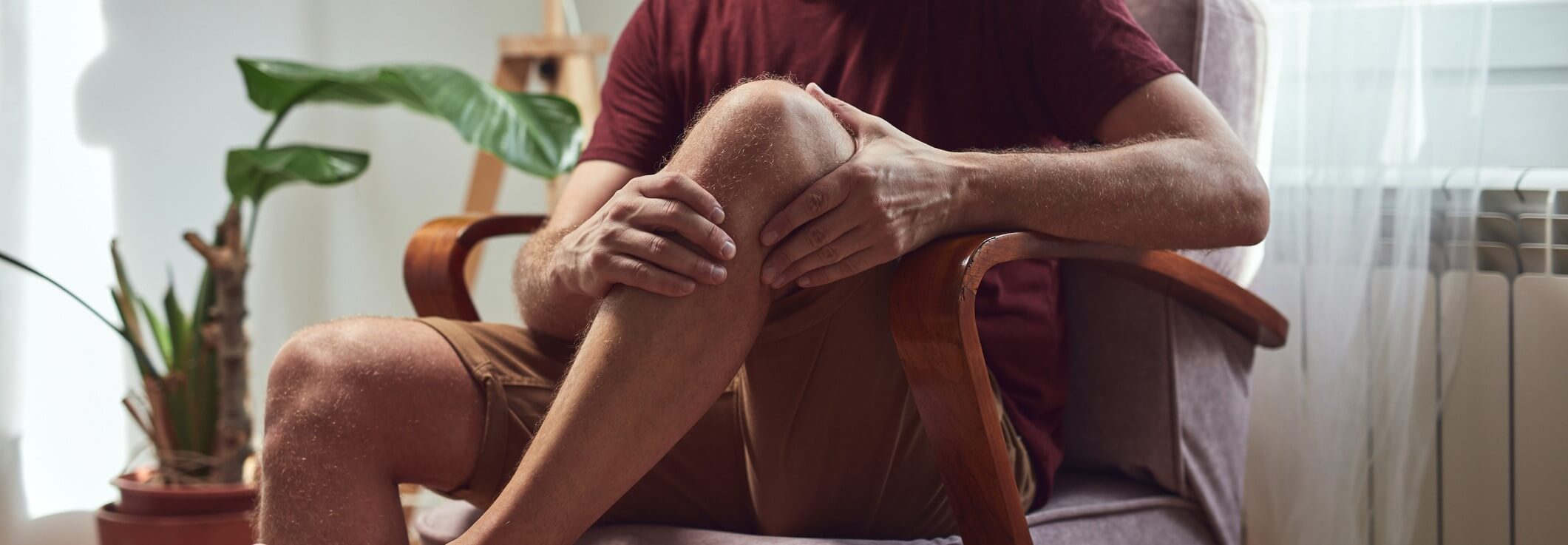A senior man holds his knee from patella alta