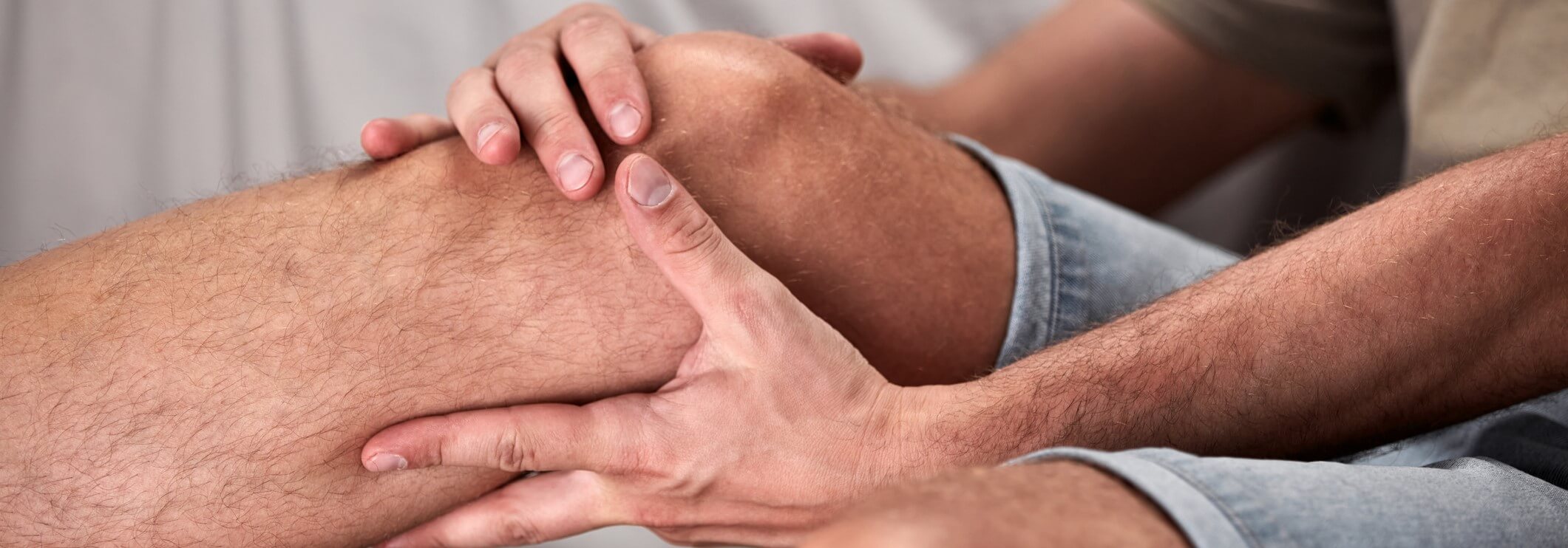 A senior man holds his knee while in pain