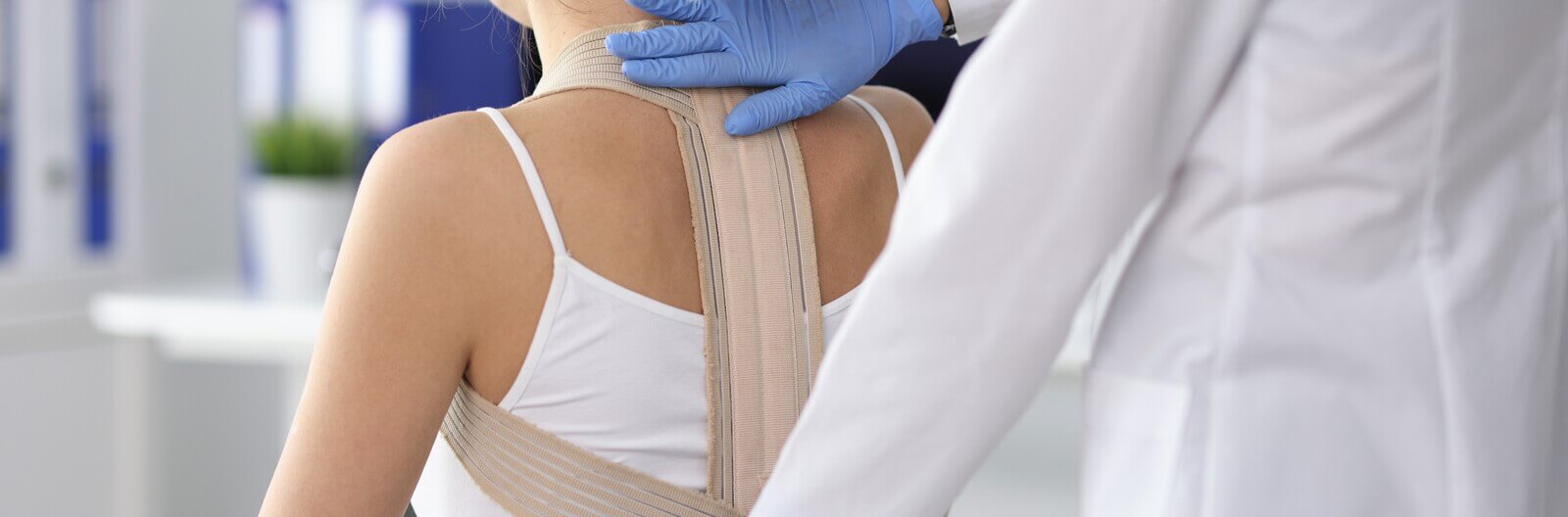 Doctor placing back brace on patient with clavicular fracture 